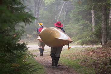 Two people carrying their kayaks through a trail. Gifts of Real Estate Two people carrying their kayaks through a trail. Gifts of Real Estate