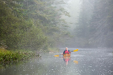 A man canoeing in a river in the rain. Links to Gifts from Retirement Plans A man canoeing in a river in the rain. Links to Gifts from Retirement Plans
